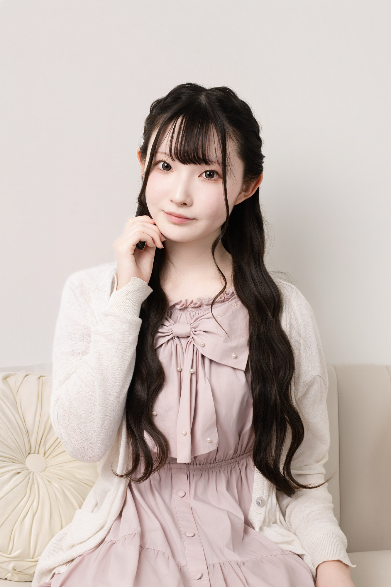ピンクの私服と白いカーディガンで落ち着いた表情を見せるプロフィール写真